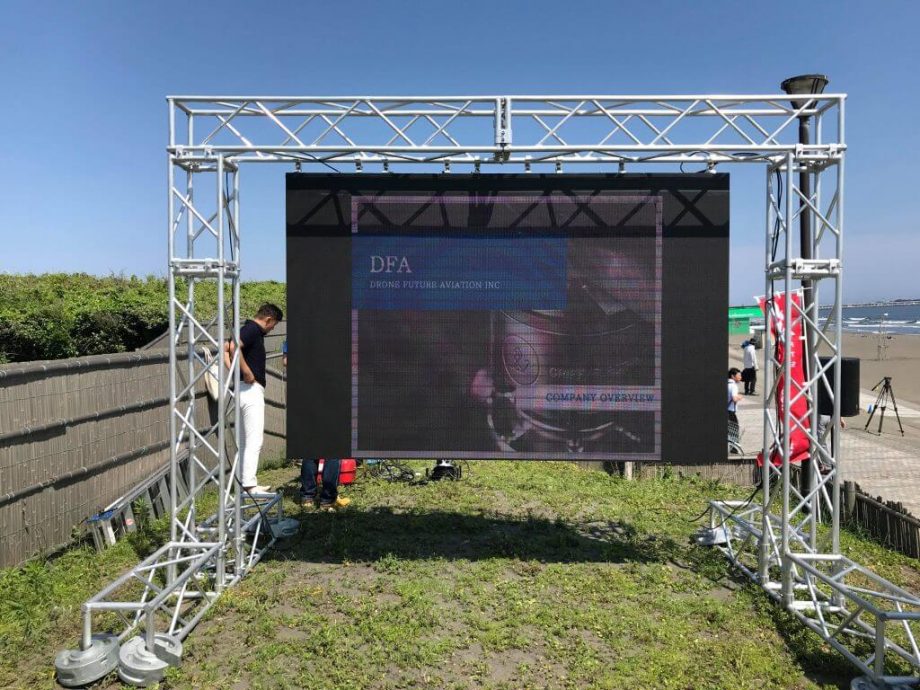 insait砂浜のすぐ近く、強い海風の吹くなか、不整地に屋外用LEDディスプレイを設営しました。安全性を確保するためトラスの足元を調整し、バランスを整えてからLEDディスプレイを吊り下げています。 砂浜のすぐ近く、強い海風の吹くなか、不整地に屋外用LEDディスプレイを設営しました。安全性を確保するためトラスの足元を調整し、バランスを整えてからLEDディスプレイを吊り下げています。